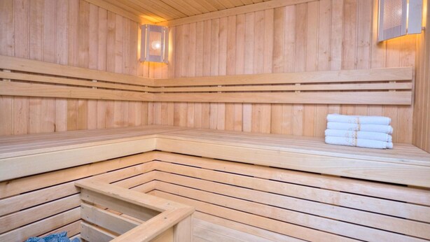 A wooden sauna with benches and a bench with towels. - Golden Gate Inn (Kyiv)