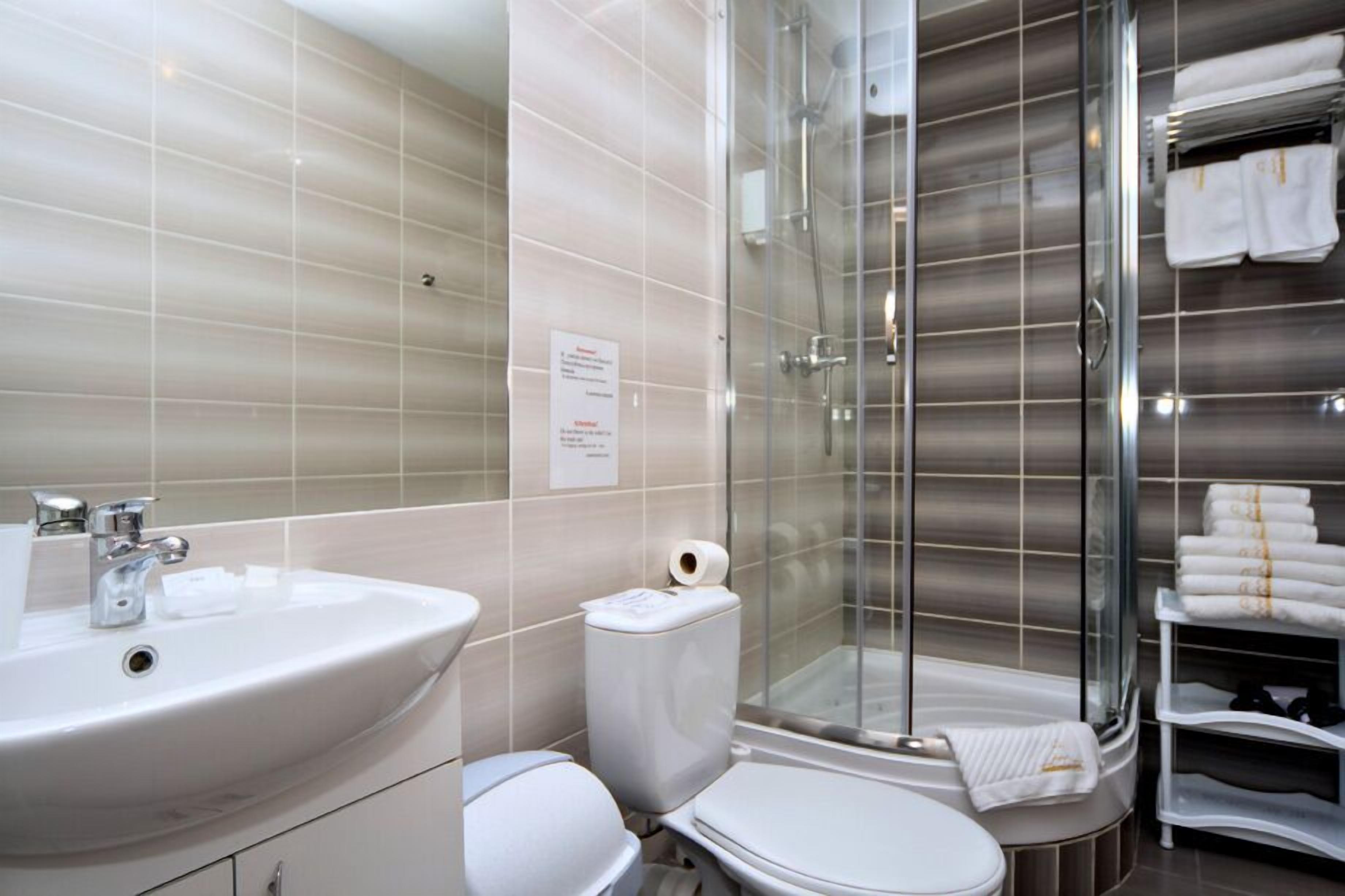 Ein modernes Badezimmer mit einem großen Waschbecken, Toilette und einer Duschkabine aus Glas.