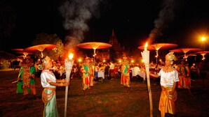 A group of people in traditional attire performing a ritual with torches and umbrellas. - Amazing Bagan Resort (Nyaung-U)