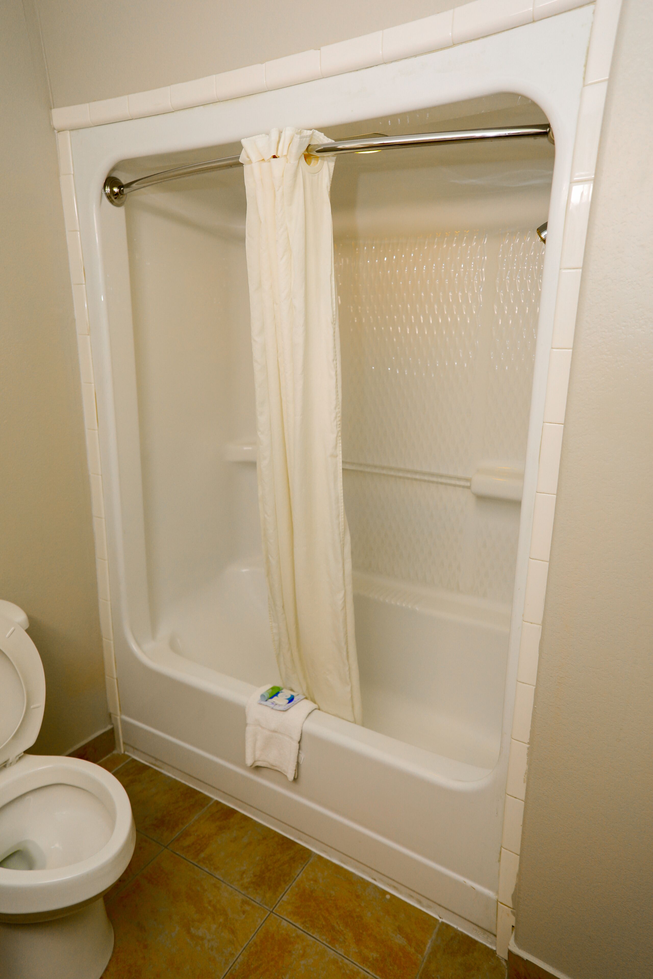 A bathroom with a bathtub, toilet, and shower curtain.