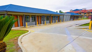 Fileira de edifícios de motel com telhado azul, estacionamento e uma palmeira.