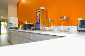 A counter with a coffee machine, a juice dispenser, and two glass jars.