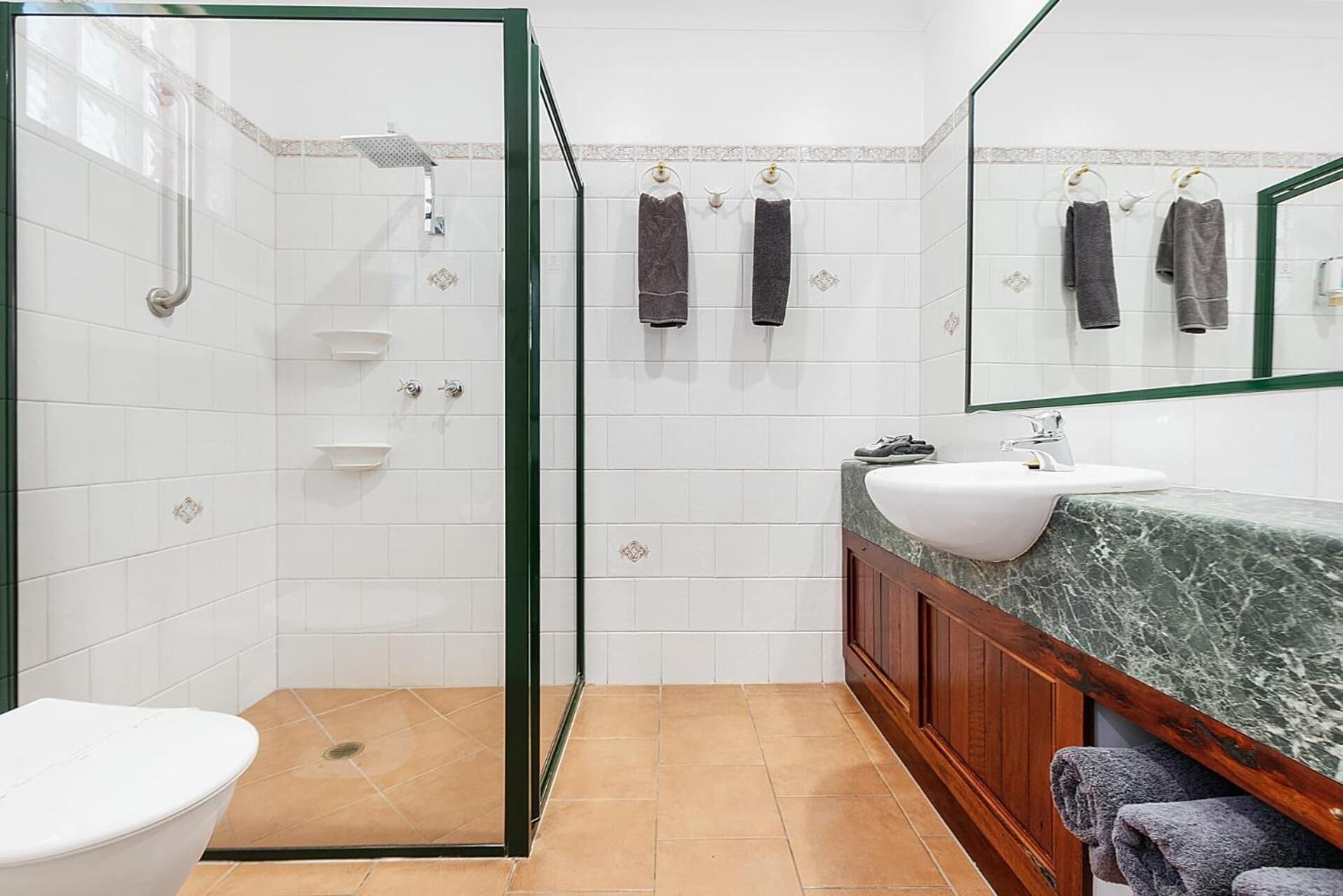 A bathroom with a glass-enclosed shower, a white sink, and a toilet.