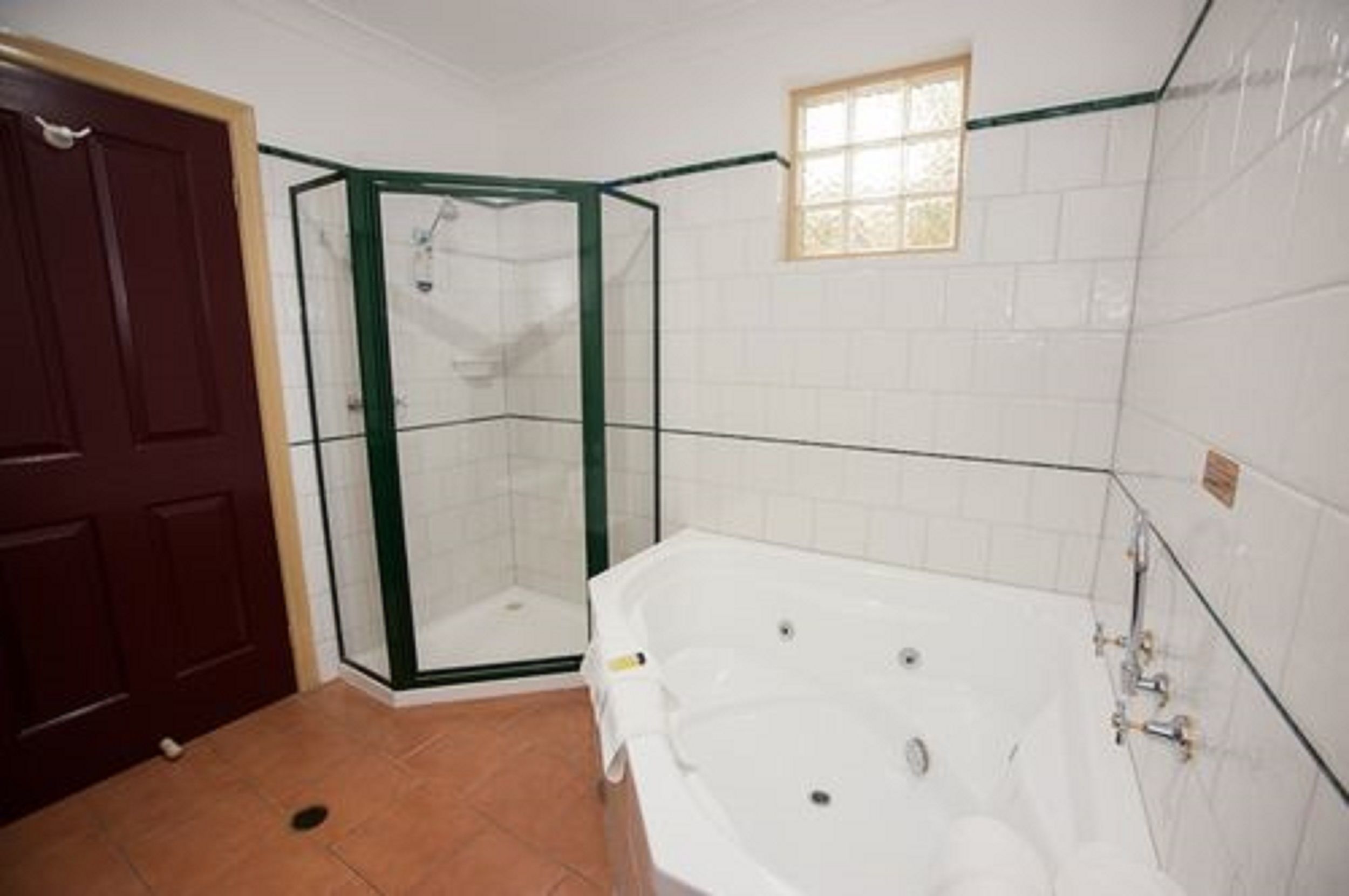 A bathroom with a glass shower enclosure, a white bathtub, and a door.