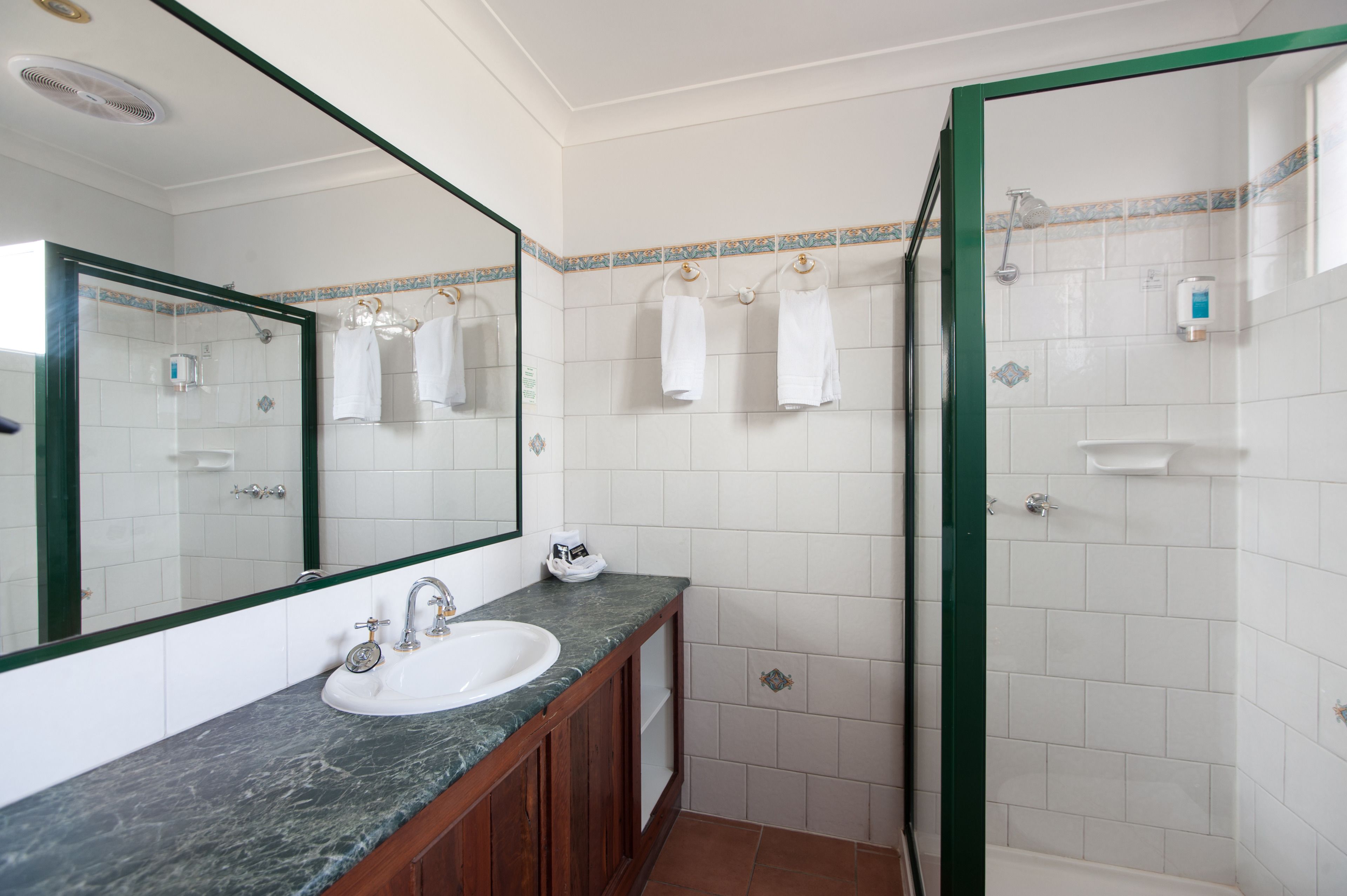 Un baño con lavamanos, espejo y ducha.