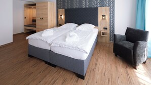 Une chambre d’hôtel moderne avec un grand lit, une armoire, une chaise et un mur décoré d’un motif.