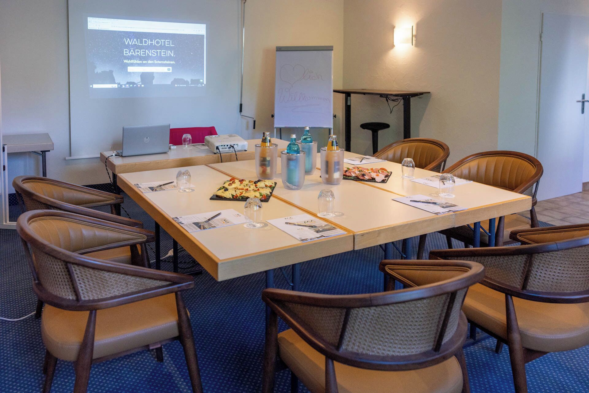 A conference room with a long table, chairs, a projector screen, and a whiteboard.