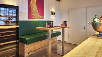 Una habitación de hotel moderna con un sofá verde, una mesa de madera y un minibar.