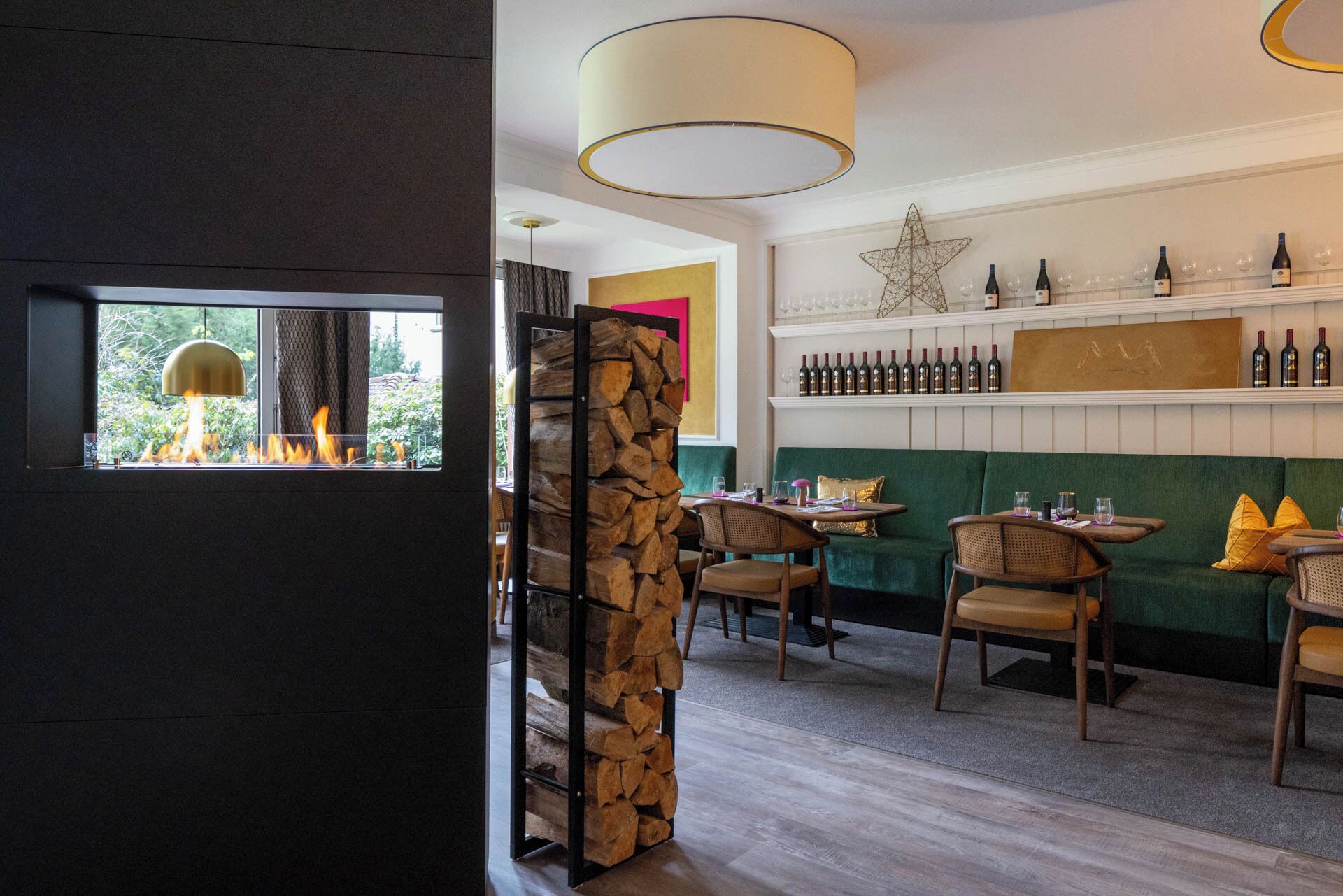Interior acogedor de un restaurante con chimenea, muebles de madera y una vitrina con vino en la pared.