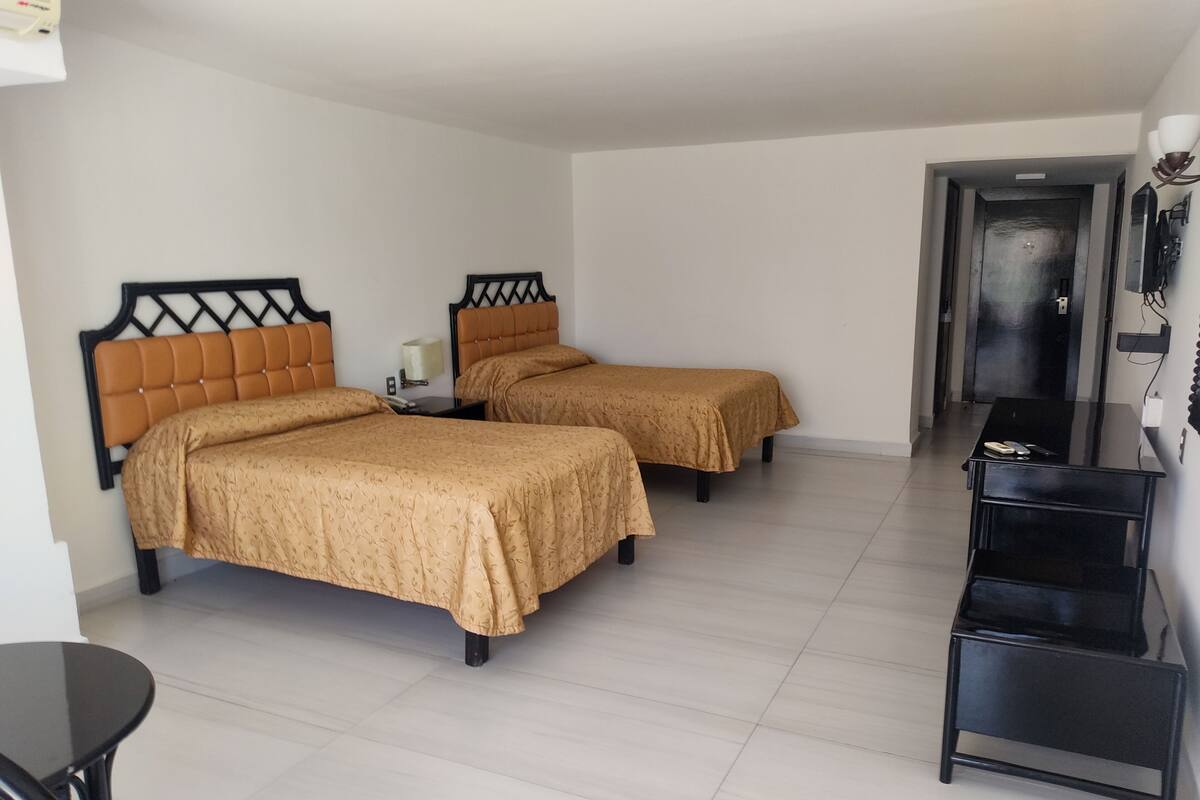 A hotel room with two beds, a desk, and a chair.