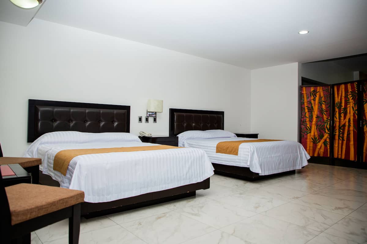 A hotel room with two beds, a desk, and a chair.