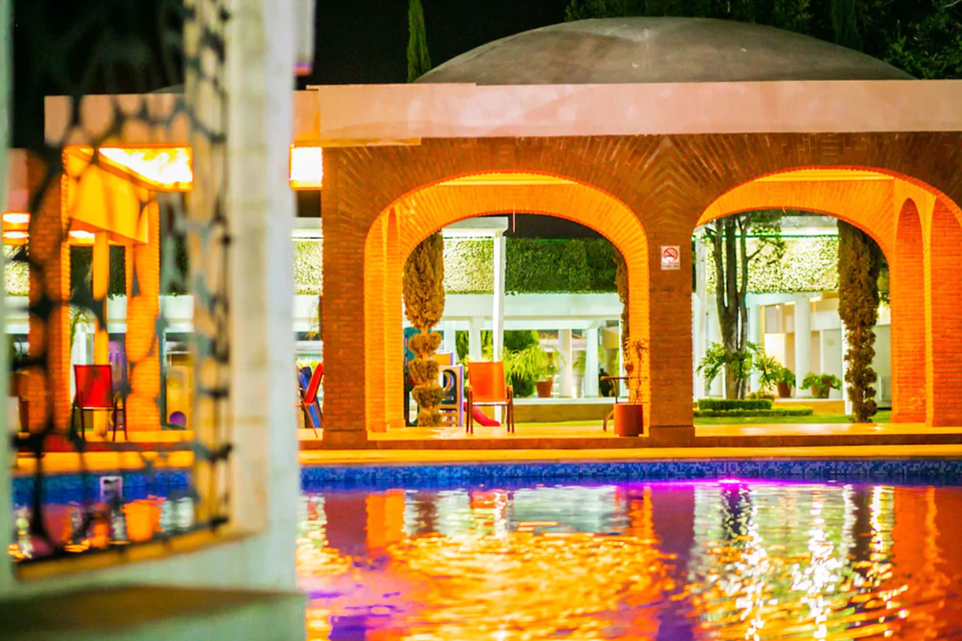A building with a pool, featuring arched windows and a dome structure.