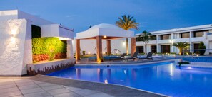 A modern pool area with lounge chairs, a covered seating area, and a well-maintained garden wall. - Hotel María Dolores San Luis Potosí (San Luis Potosi)