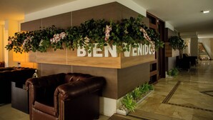 A reception area with a 'Bien Venidos' sign, a brown leather couch, and a plant wall.