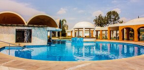 A swimming pool with a tiled deck, surrounded by buildings with arched structures and a clear sky. - Hotel María Dolores San Luis Potosí (San Luis Potosi)