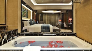 A luxurious hotel room with a large bed, a sitting area, and a bathtub with rose petals. - Howard Johnson Agile Plaza Chengdu (Chengdu)