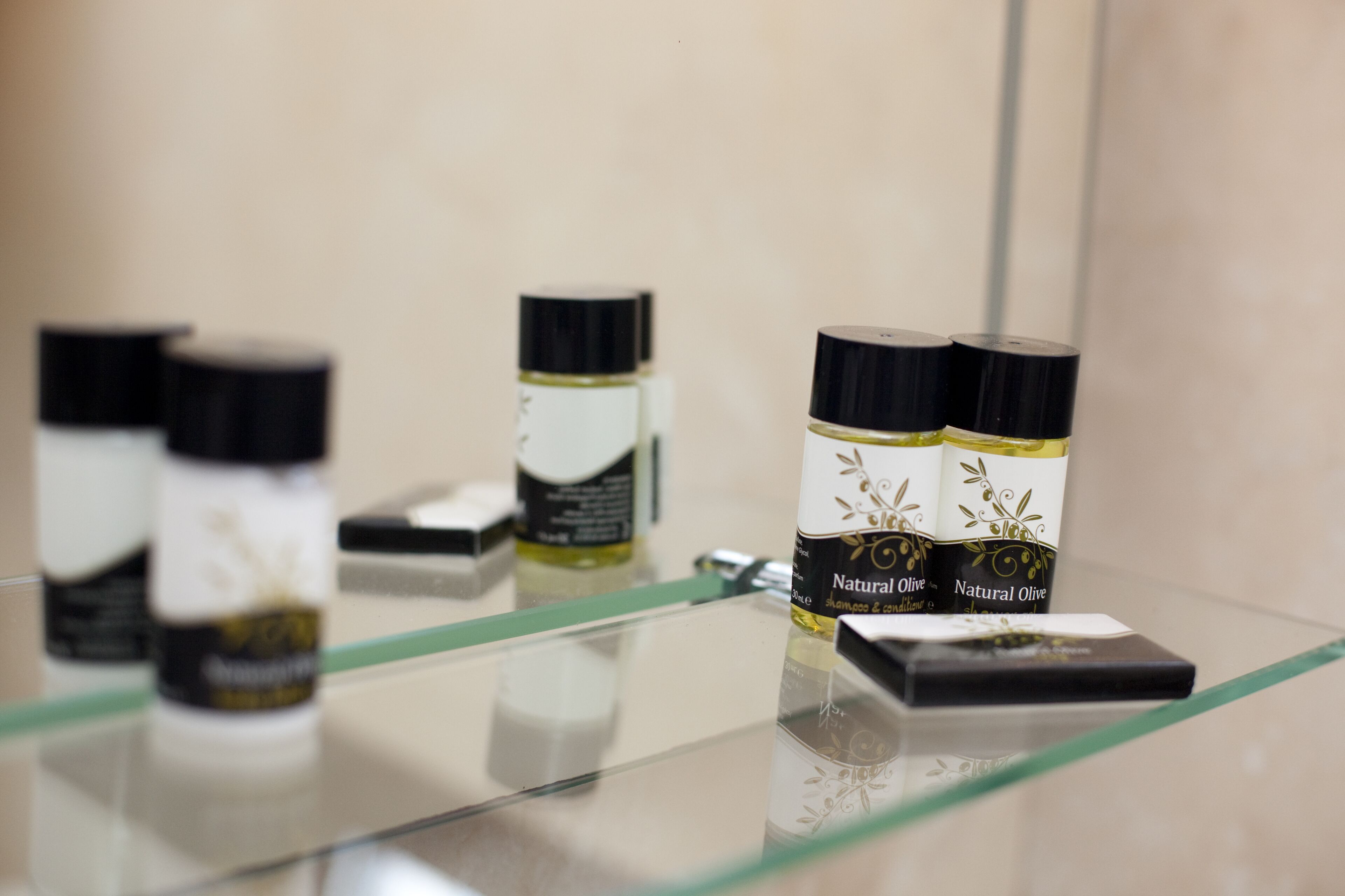 Une collection de bouteilles d’huile d’olive naturelle est exposée sur une étagère en verre.
