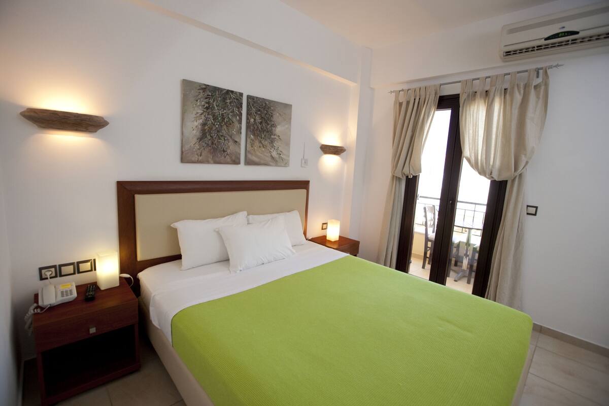 A hotel room with a bed, bedside lamps, a telephone, and artwork on the wall.