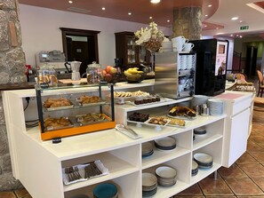 Un bufé de desayuno con diversos pasteles, frutas y bebidas.