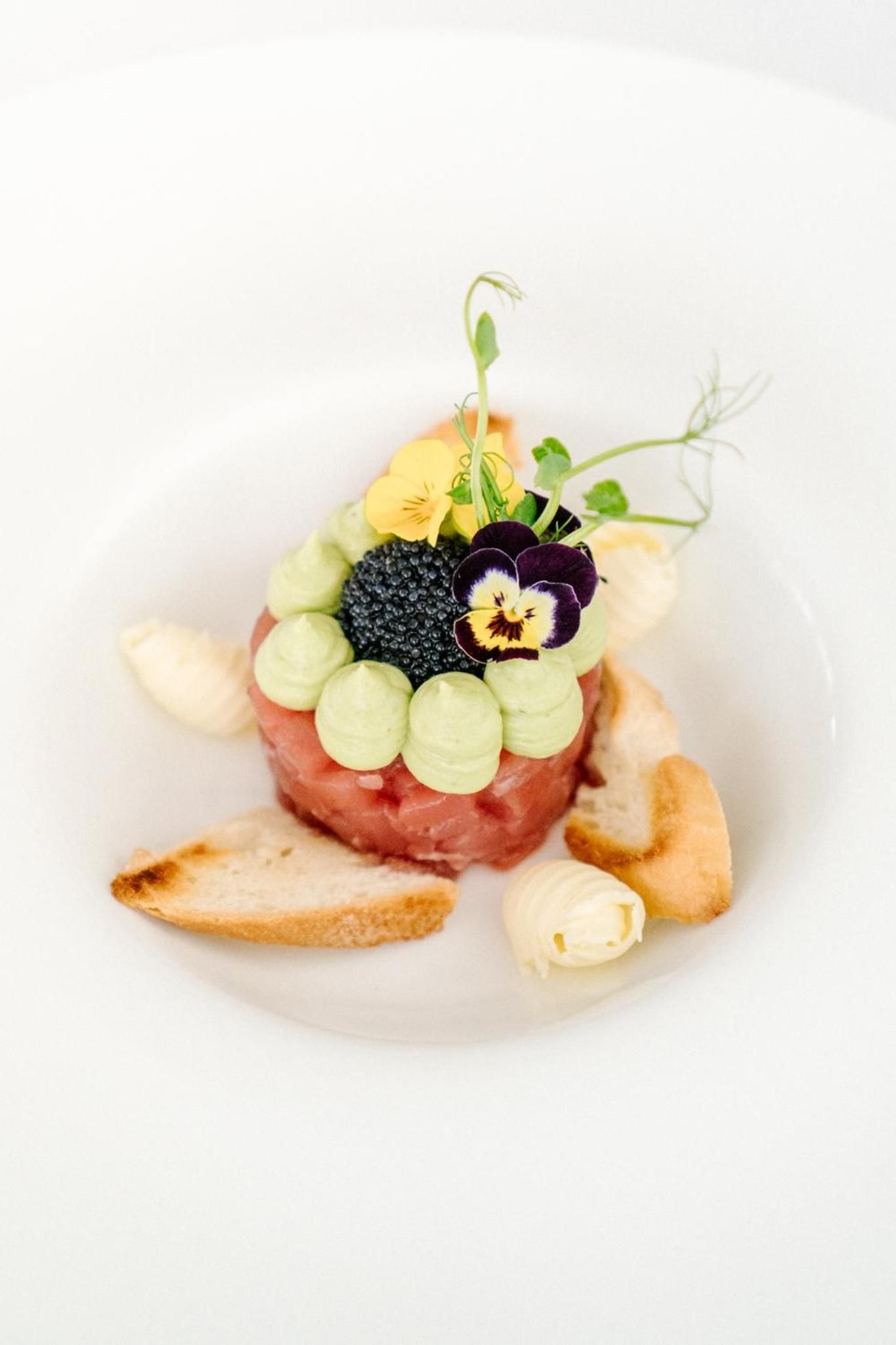 A plated dish with a variety of ingredients including meat, vegetables, and a decorative flower.