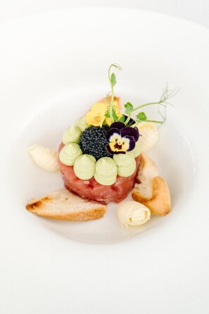 A plated dish with a variety of ingredients including meat, vegetables, and a decorative flower.