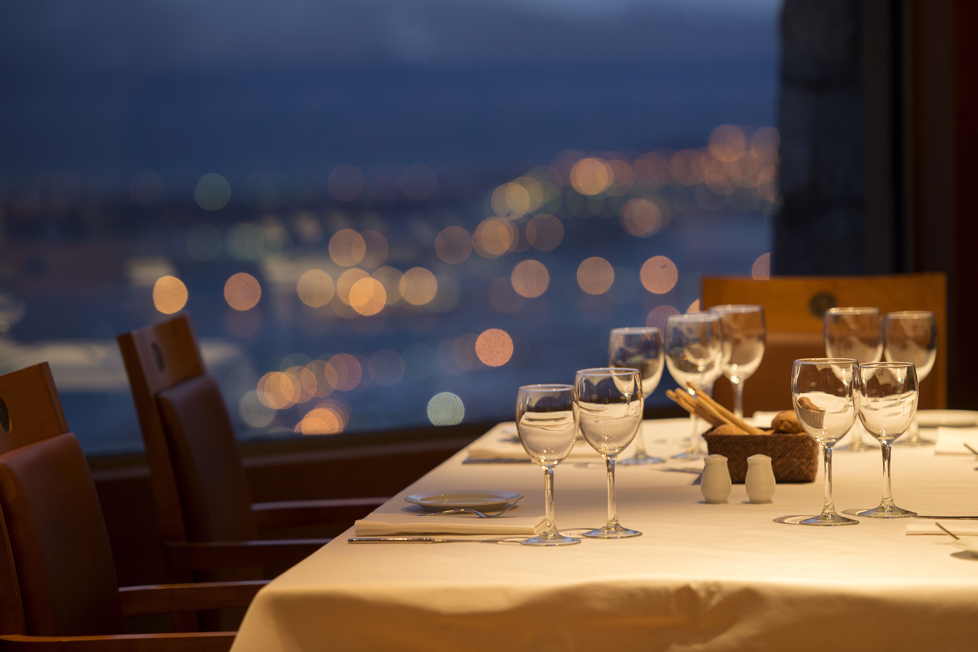 A table set for dining with glasses and cutlery, a salt and pepper set, and a bread basket.