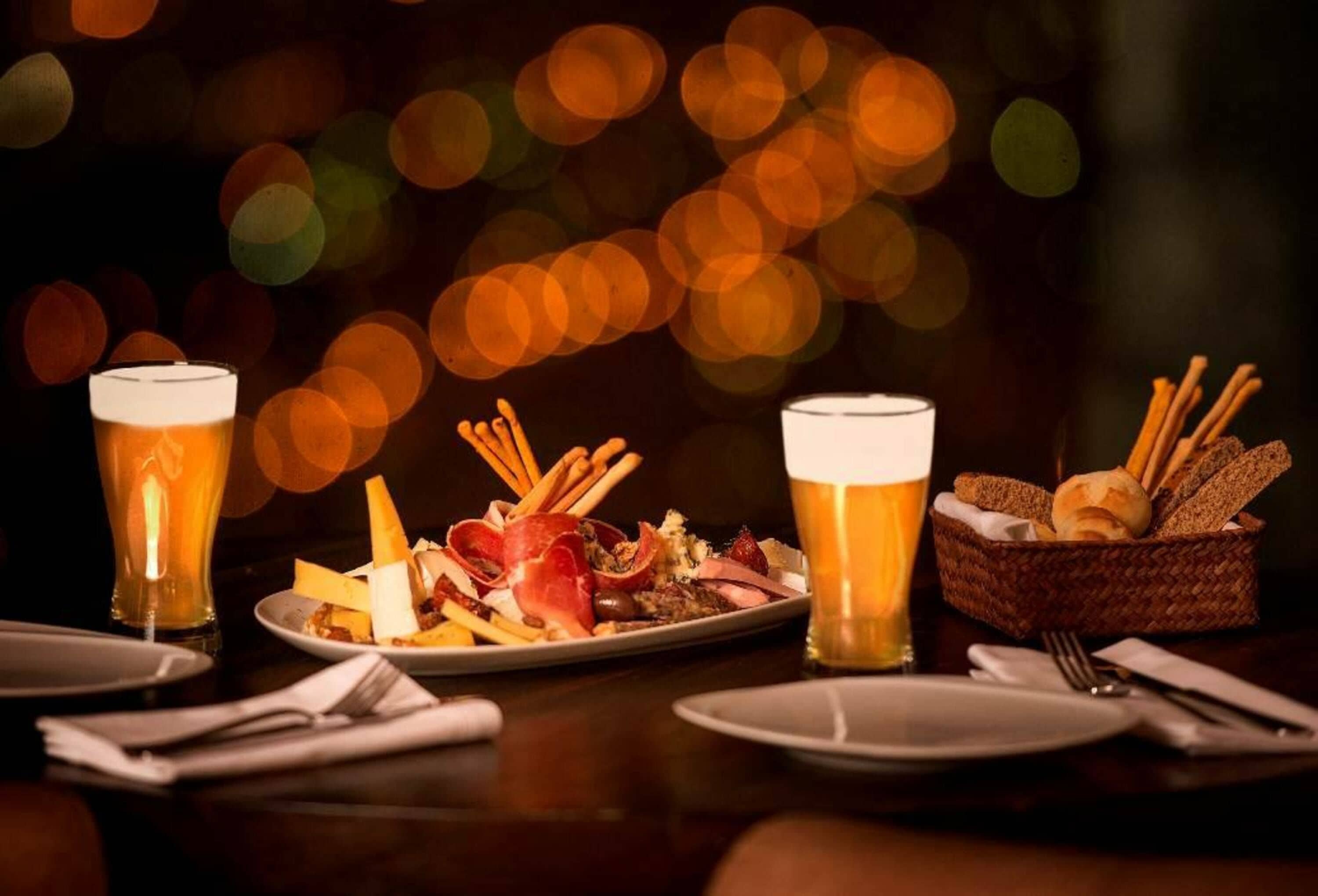 Ein Esstisch mit zwei Biergläsern, einem Teller mit Essen und einem Brotkorb.