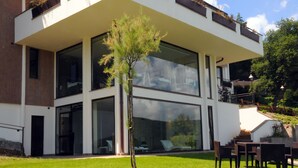 A modern two-story building with large glass windows, a grassy lawn, outdoor seating, and a staircase leading to an upper level. - Relais Sans Souci and Spa (Ronciglione)