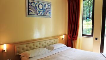 A neatly made bed with a tufted headboard, a bedside table with a phone, and a wall-mounted light fixture.