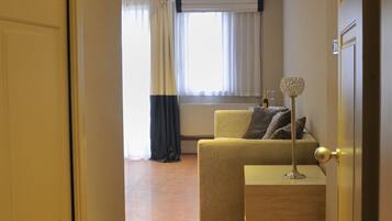 Une chambre d’hôtel avec un canapé, une petite table et une lampe décorative.