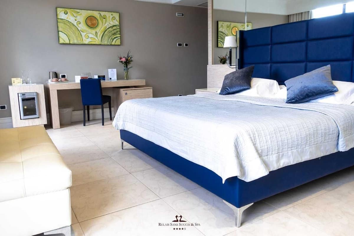 A modern hotel room with a large bed, a desk, and a chair.