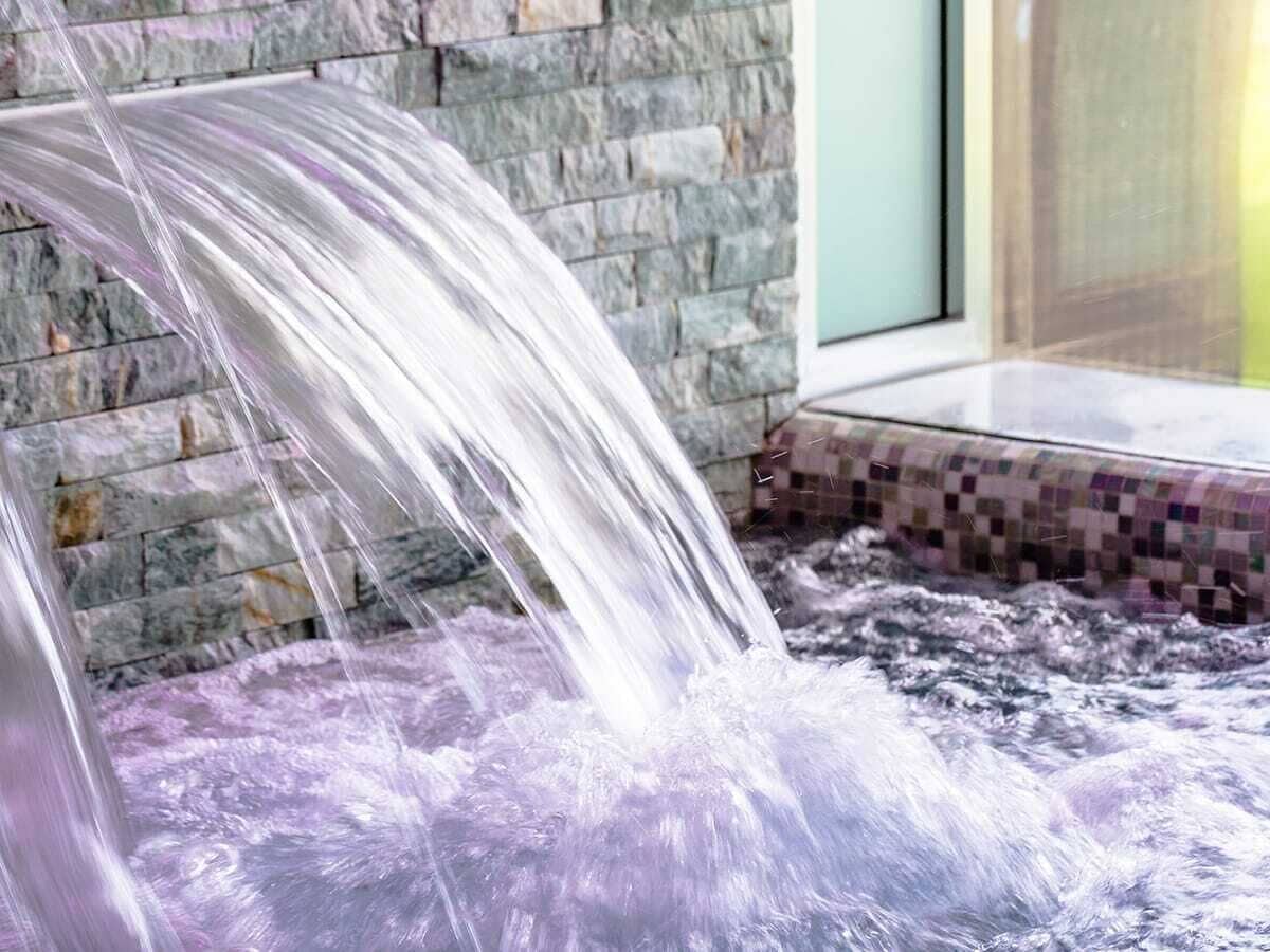 Ein Wasserspiel mit einer Steinmauer und einer gefliesten Fläche.