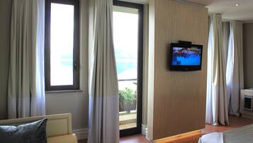 Habitación de hotel con cama, televisión montada en la pared y vistas al exterior a través de un ventanal grande.