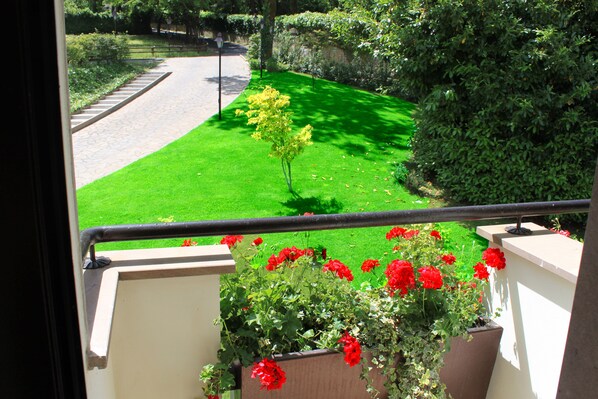 A balcony with a view of a well-maintained lawn and a road.