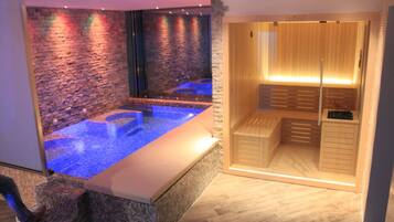 Relax in a serene spa room with a soothing water feature, a glass-enclosed shower, and a comfortable bench.
