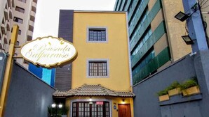 Un edificio con fachada amarilla, una pequeña entrada con techo de tejas y un cartel que dice "Pensão Balparaiso".