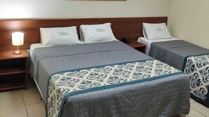 Una habitación de hotel con dos camas, una mesita de noche con lámpara y una obra de arte colgada en la pared.