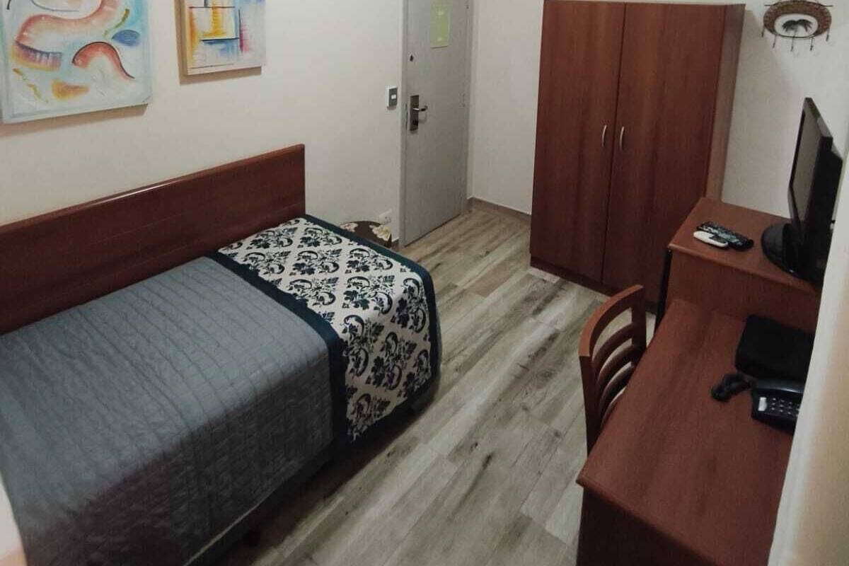 A small room with a bed, a desk, and a wardrobe.