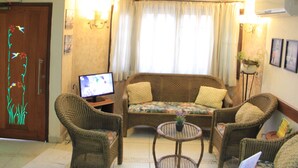 Una sala de estar con un sofá, dos sillones, una mesa de centro y una televisión.