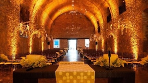 An indoor venue with a high arched ceiling, rows of chairs, a central aisle, and floral arrangements. - Hotel Hacienda Vista Hermosa (Puente de Ixtla)