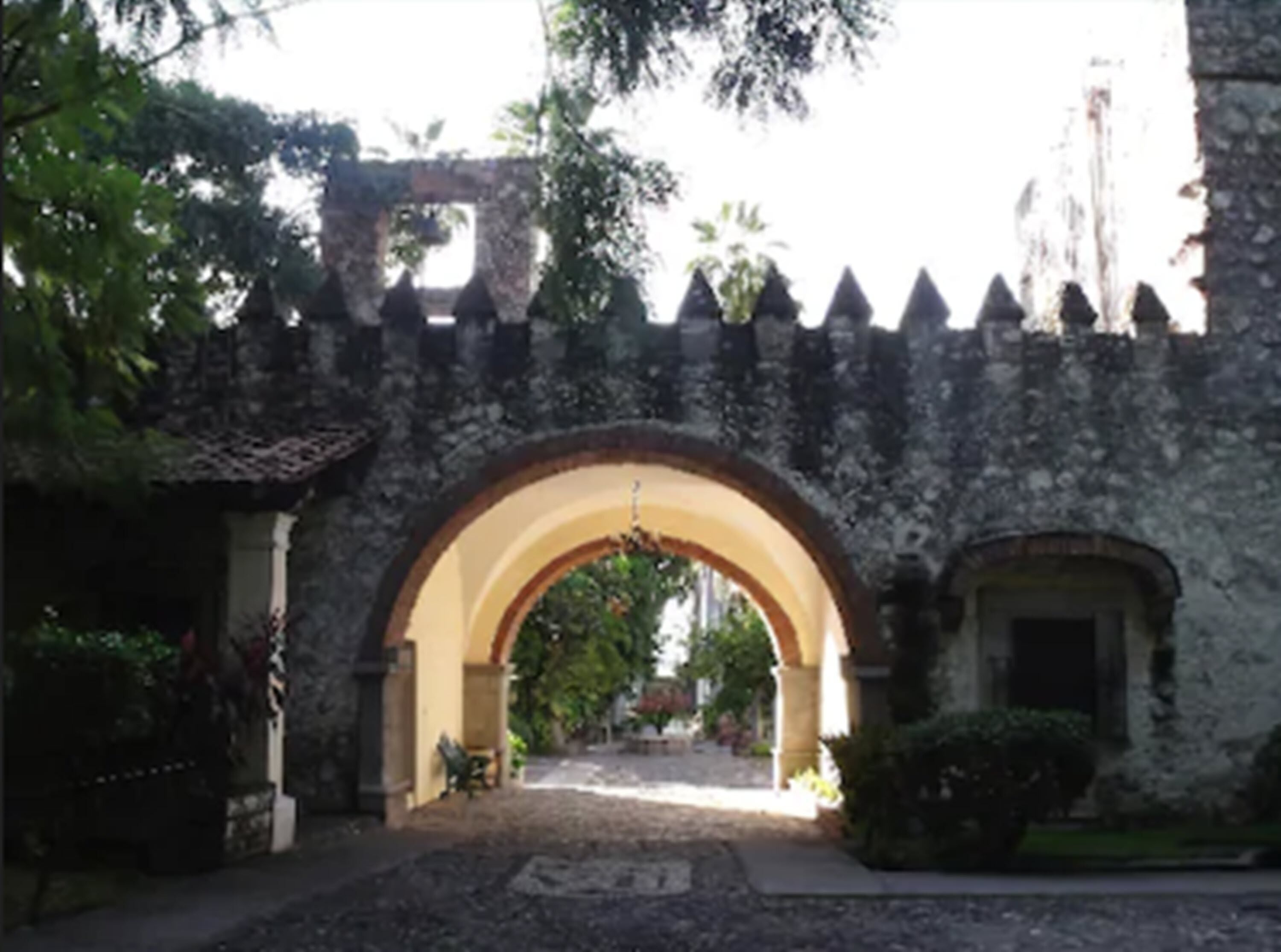 Un arco de piedra que da paso a un patio con un sendero empedrado.