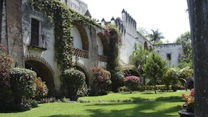 A historic building with arched windows and ivy-covered walls, surrounded by well-maintained gardens and a manicured lawn. - Hotel Hacienda Vista Hermosa (Puente de Ixtla)