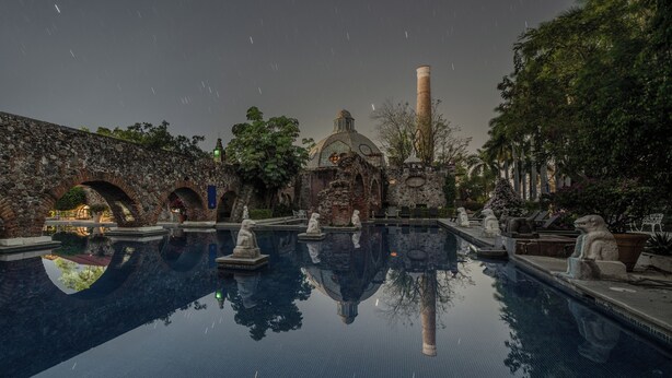 A serene pool area with stone statues, a stone bridge, and a dome structure. - Hotel Hacienda Vista Hermosa (Puente de Ixtla)