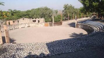 Un anfiteatro al aire libre con escenario de piedra y zona de asientos.