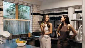 Una cocina moderna con un amplio ventanal, un cuenco de fruta sobre la encimera y electrodomésticos de acero inoxidable.