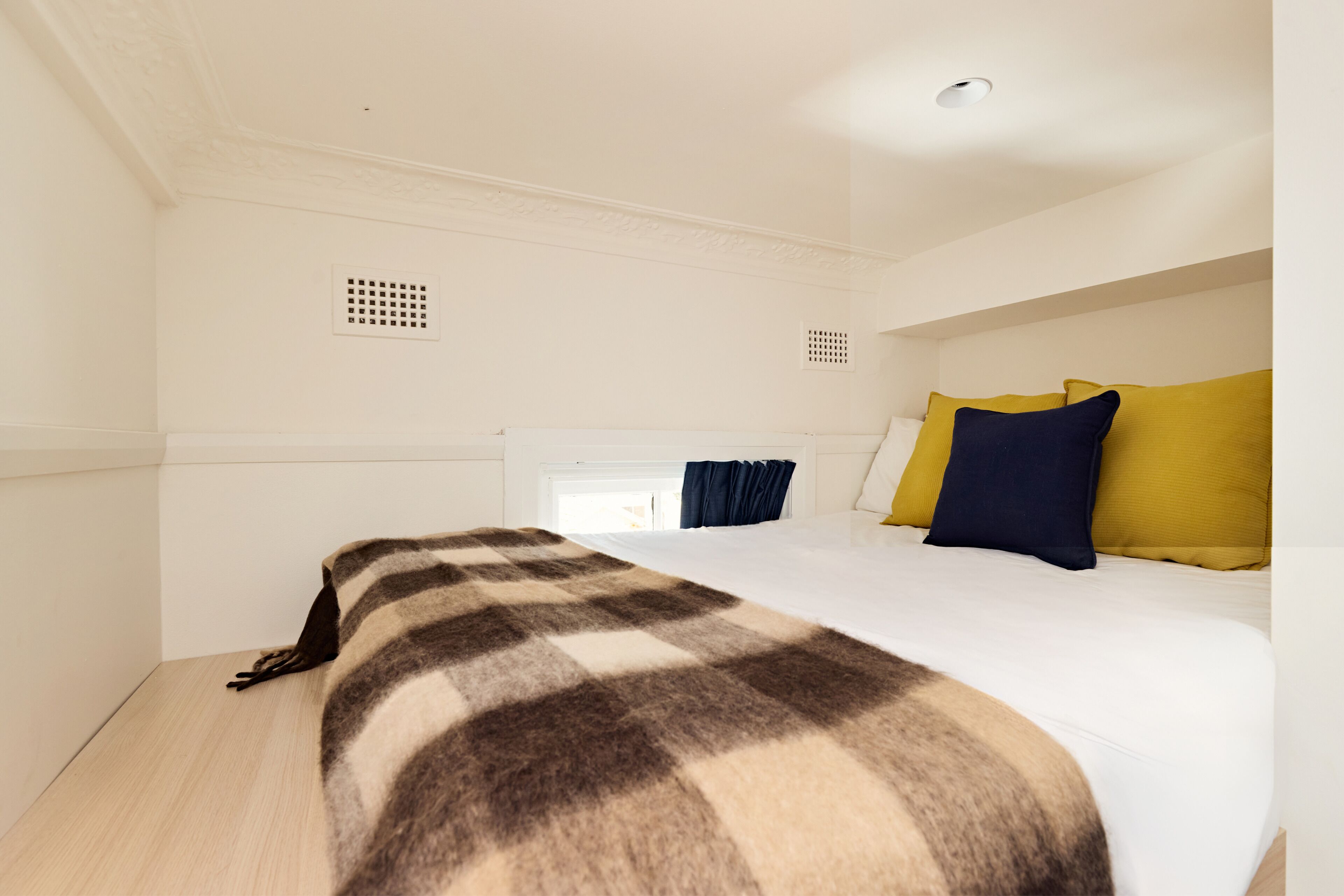 A hotel room with a large bed, white walls, and a ceiling with a recessed light fixture.