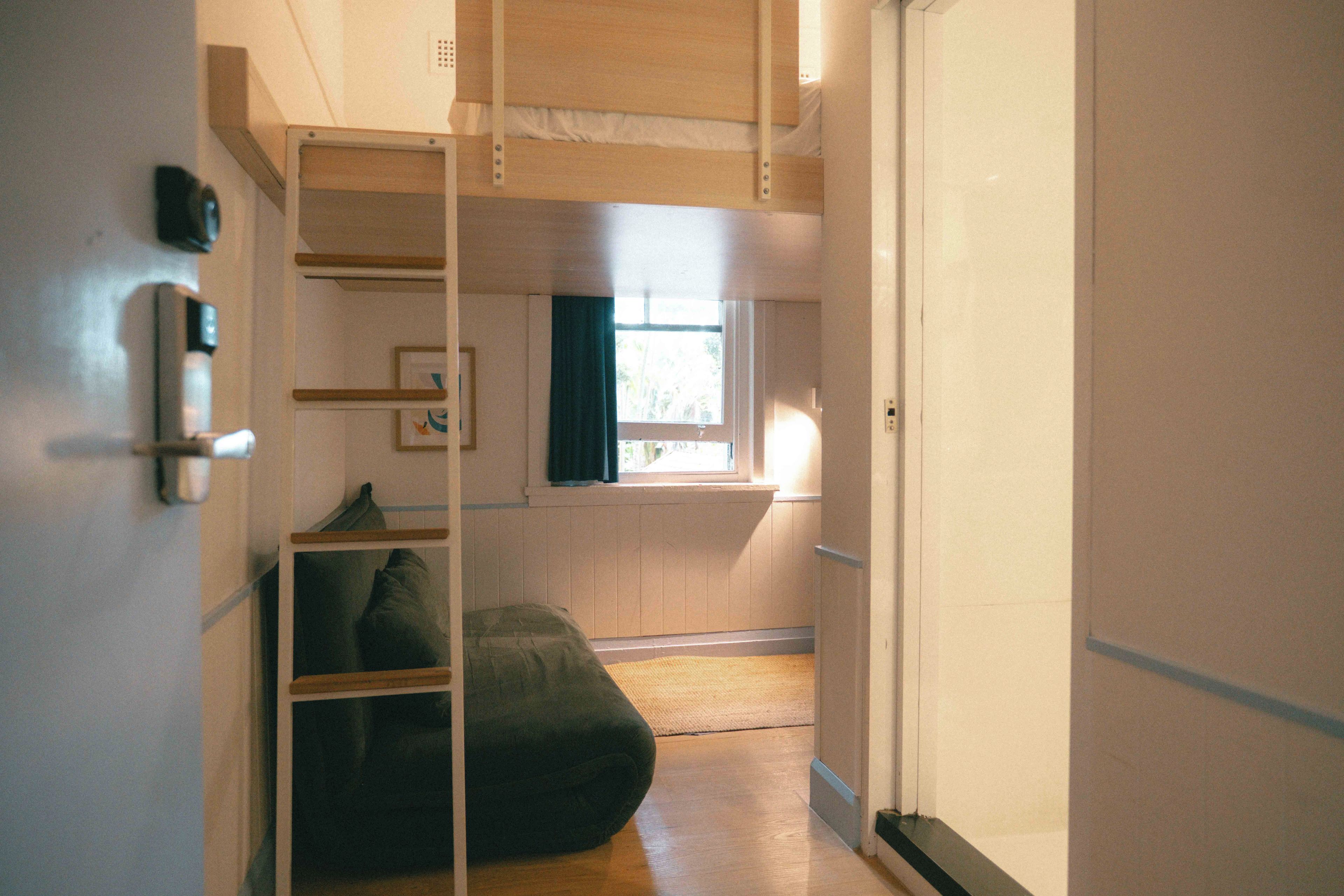 A room with a bunk bed, a small window, and a door.