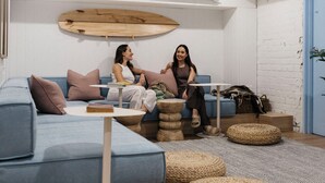 Una sala de estar moderna con un sofá azul, una mesa de centro redonda y una tabla de surf colgada en la pared.