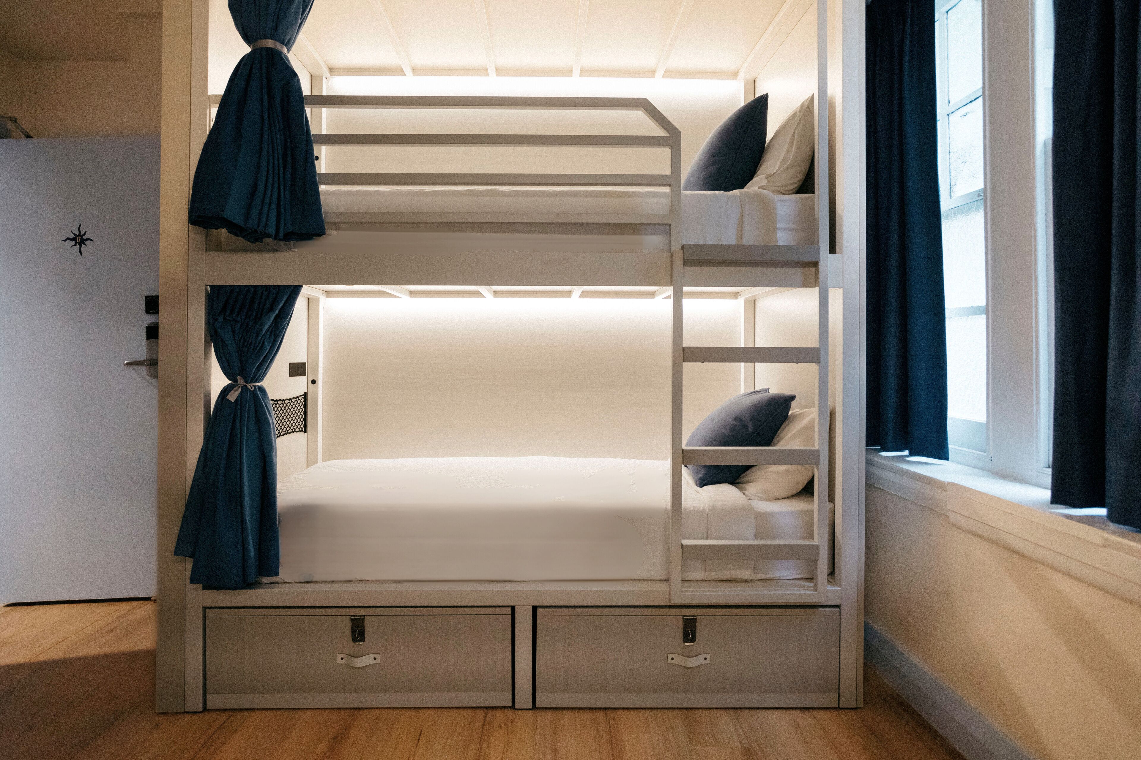 Un lit superposé avec une échelle, un bureau et des tiroirs en dessous.
