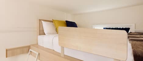 Una cama litera con cabecera de madera, ropa de cama blanca y una pequeña escalera de madera.